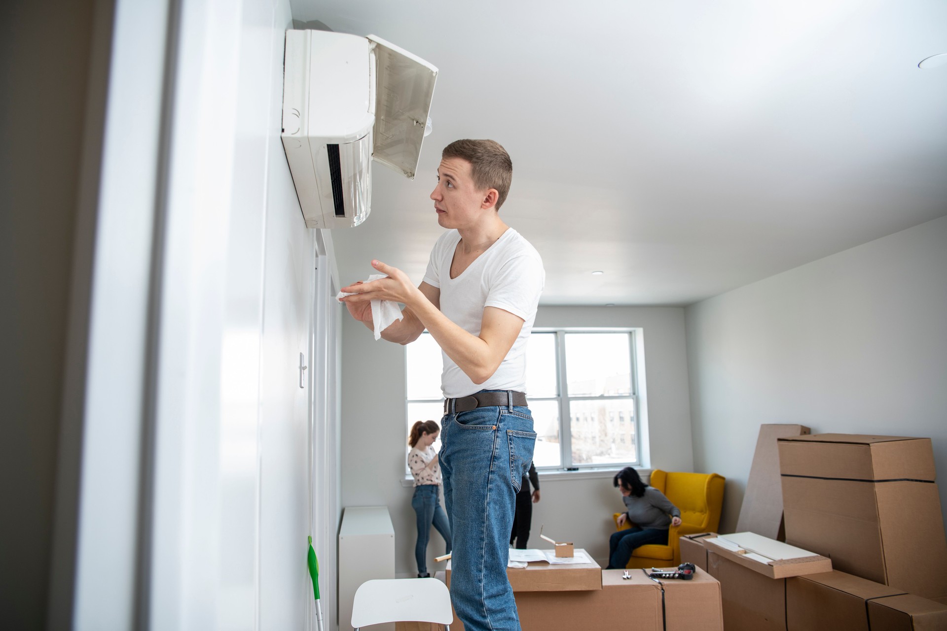 The young man cleaning filters in the air-conditioning split device in the recently rented apartment